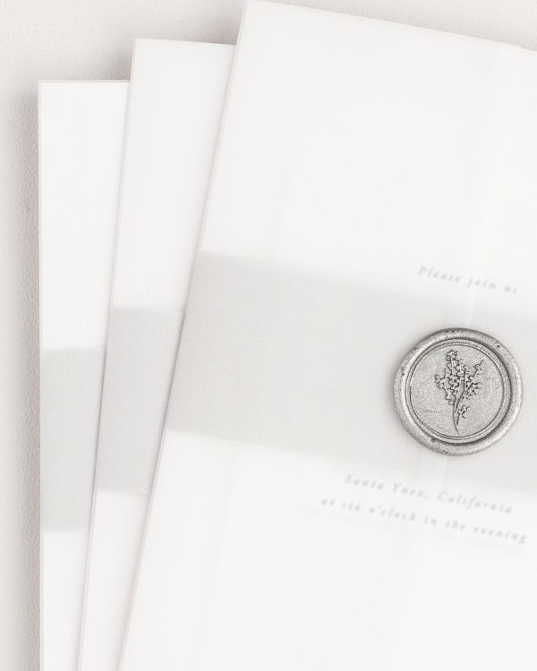 Alyssa wedding invitation with a soft gray belly band, translucent vellum jacket, and silver posy wax seal.
