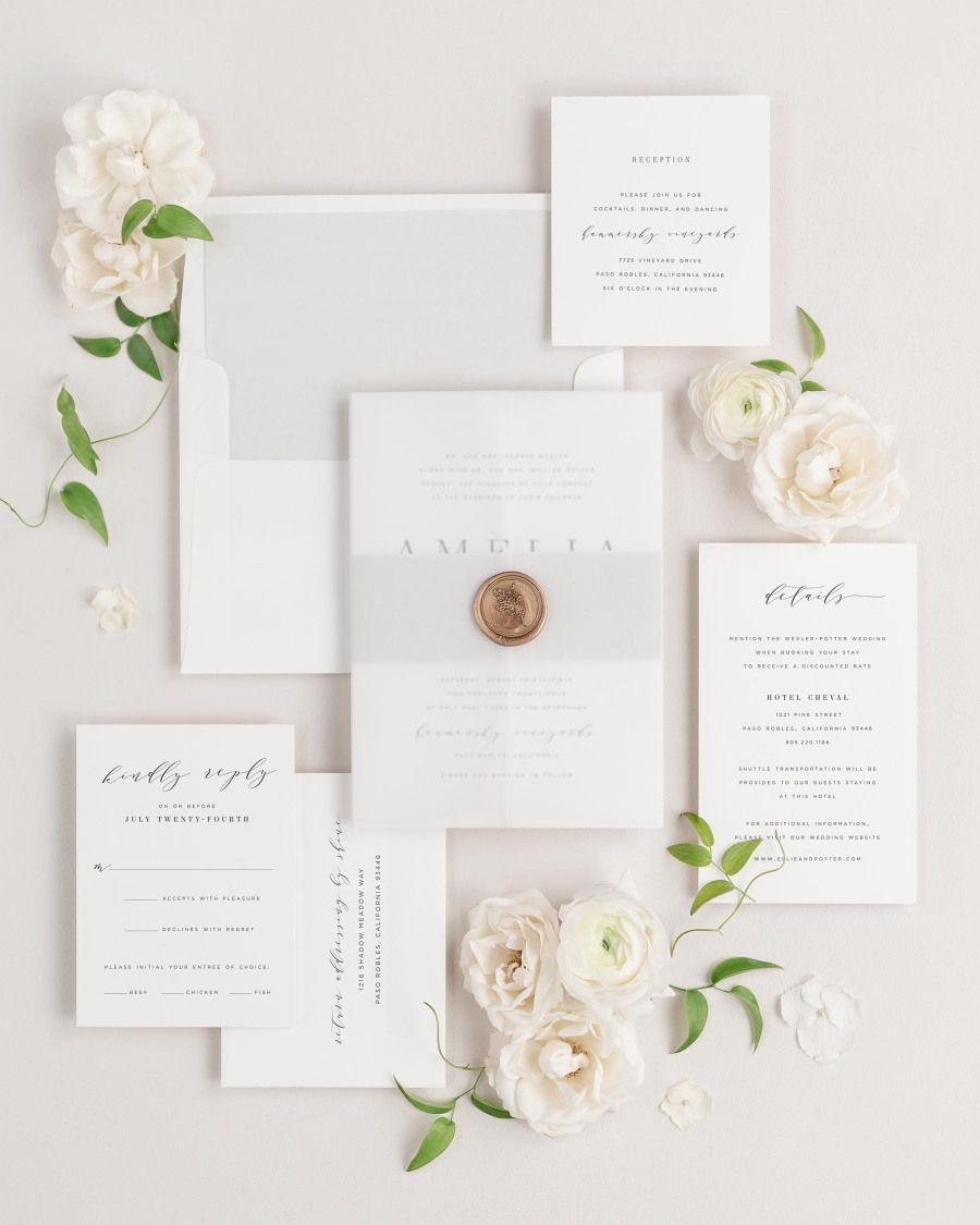 Amelia wedding invitations flat lay with soft gray solid liner, soft gray belly band, translucent vellum jacket, and gold posy wax seal.