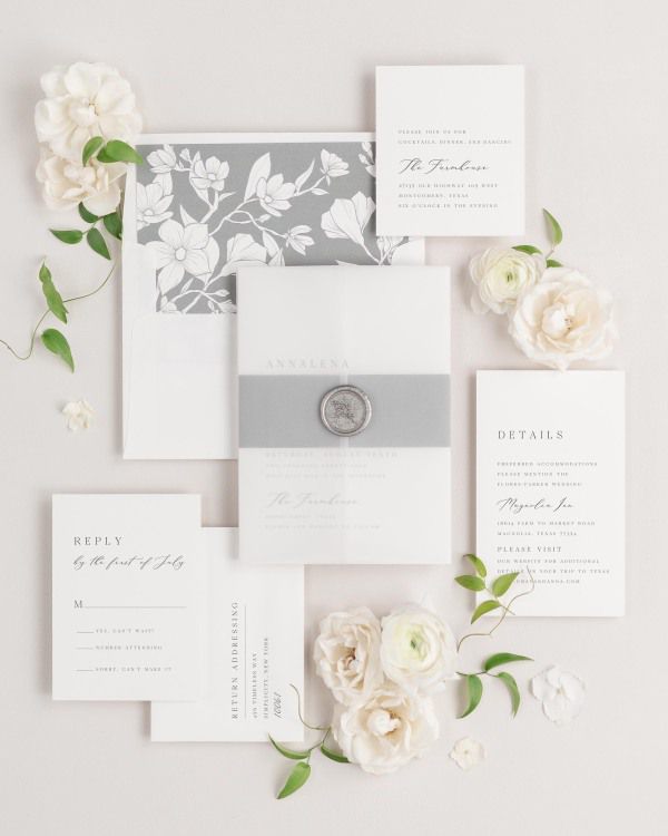 Annalena wedding invitations flat lay with slate magnolia liner, slate belly band, translucent vellum jacket, and silver posy wax seal.