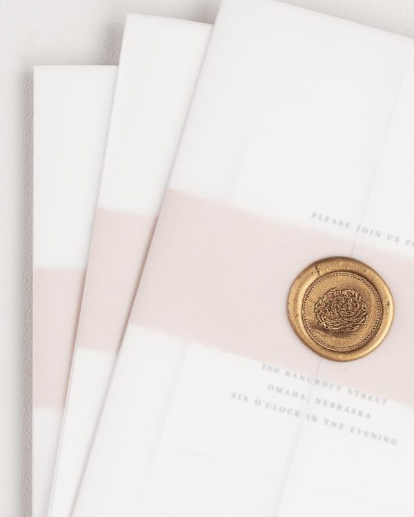 Austin wedding invitation with a rose gold belly band, translucent vellum jacket, and gold florette wax seal.