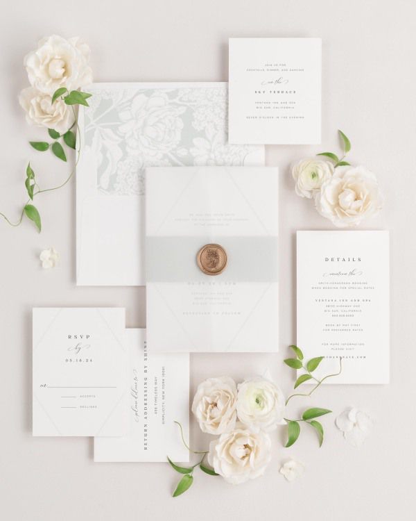 Bethany wedding invitations flat lay with sea salt hydrangea liner, sea salt belly band, translucent vellum jacket, and gold posy wax seal.