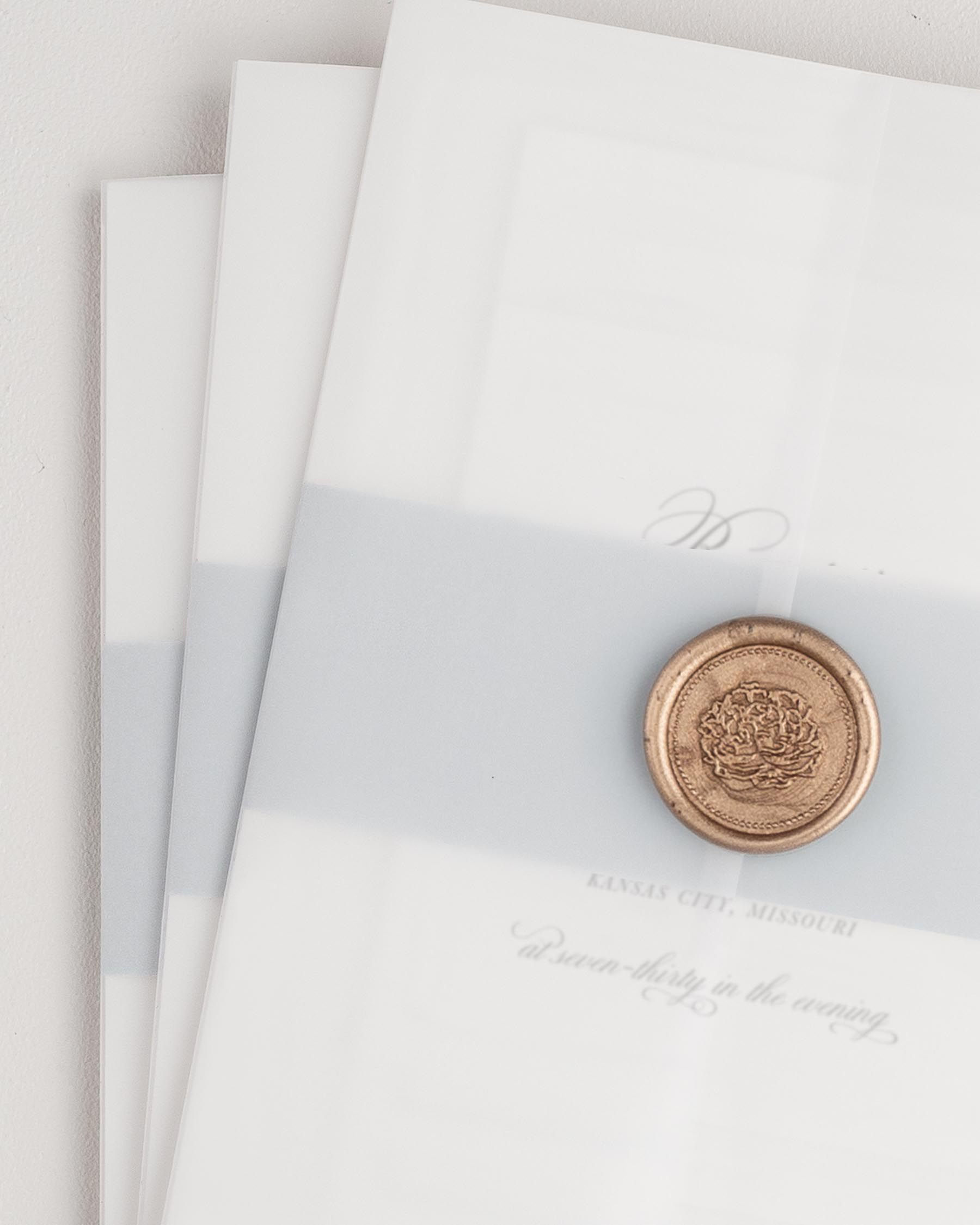 Classic Script wedding invitation with a cloud belly band, translucent vellum jacket, and gold florette wax seal.