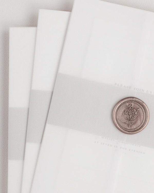 Claudia wedding invitation with a stone belly band, translucent vellum jacket, and wax seal.