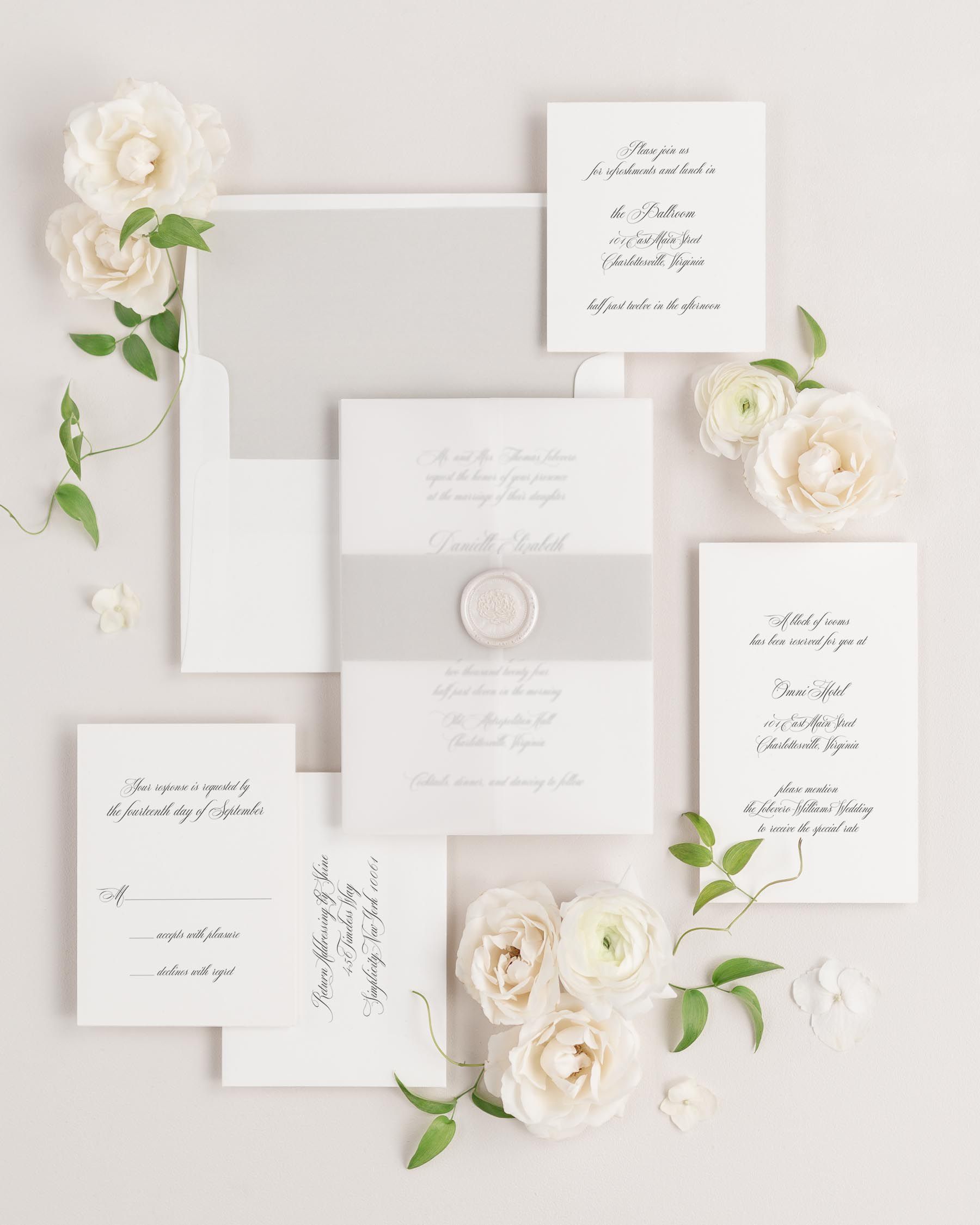 Danielle wedding invitations flat lay with stone solid liner, stone belly band, translucent vellum jacket, and pearl florette wax seal.