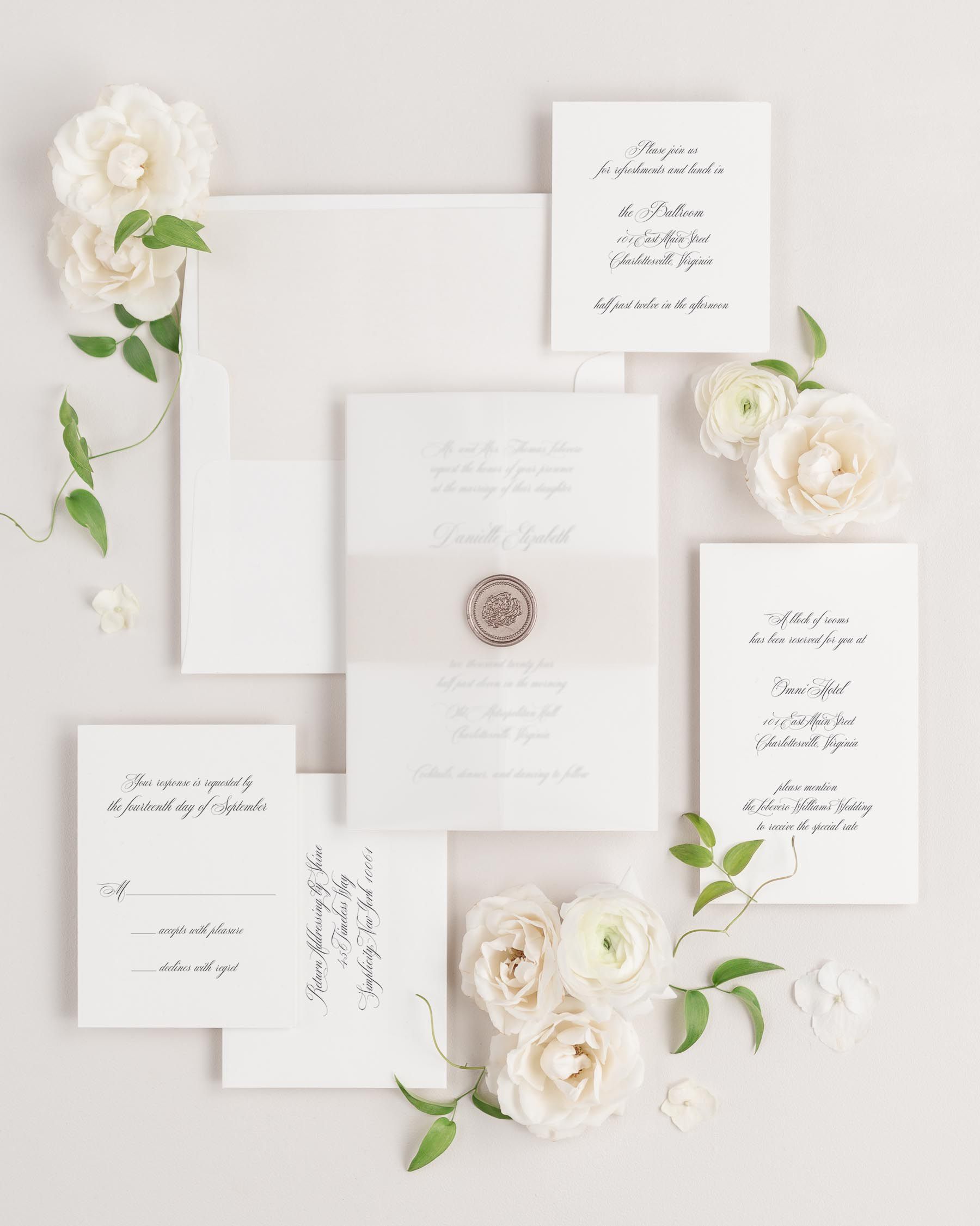Danielle wedding invitations flat lay with nude solid liner, nude belly band, translucent vellum jacket, and bronze florette wax seal.