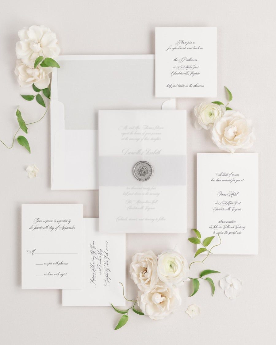Danielle wedding invitations flat lay with soft gray solid liner, soft gray belly band, translucent vellum jacket, and silver florette wax seal.