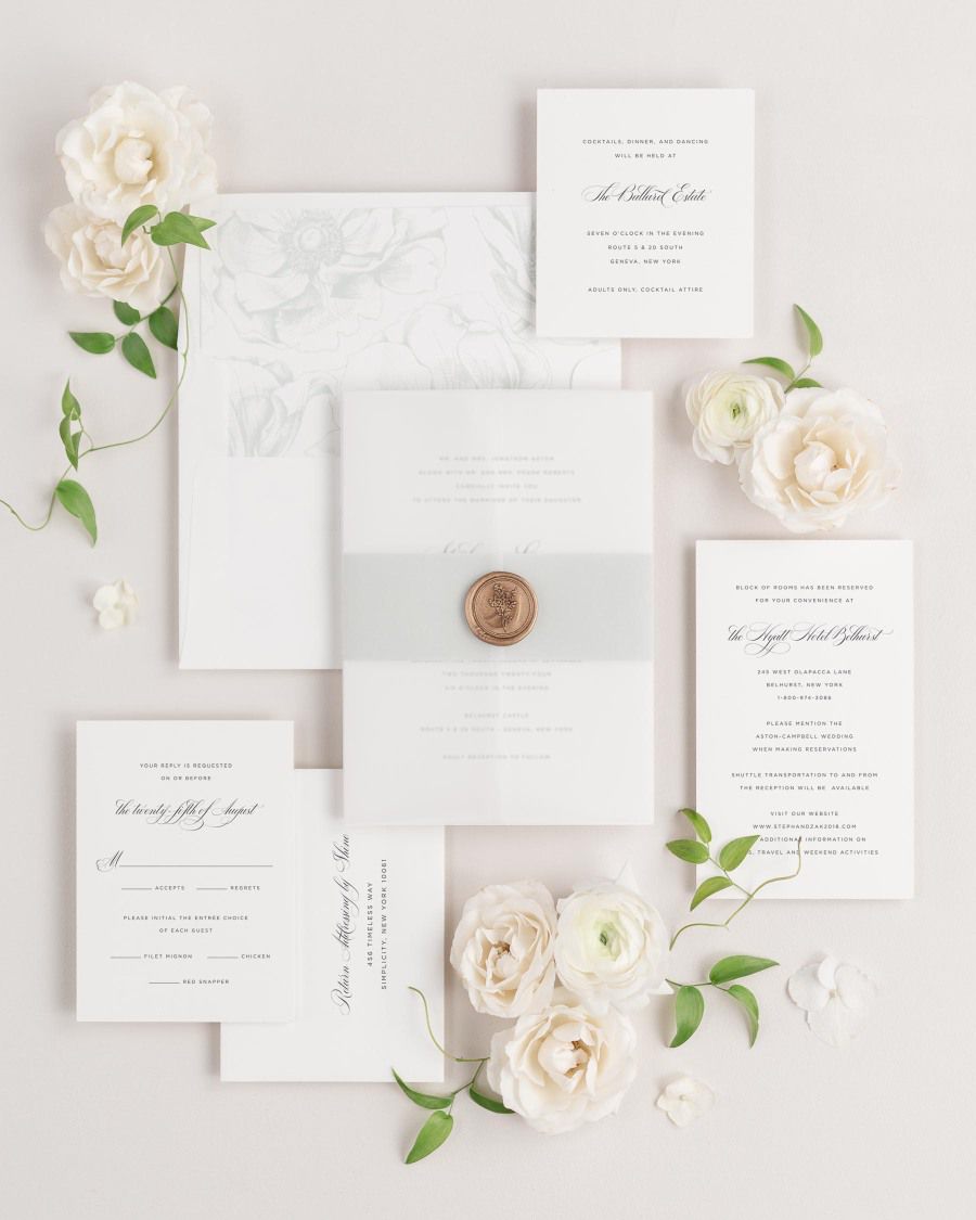 Delicate Elegance wedding invitations flat lay with sea salt anemones liner, sea salt belly band, translucent vellum jacket, and gold posy wax seal.