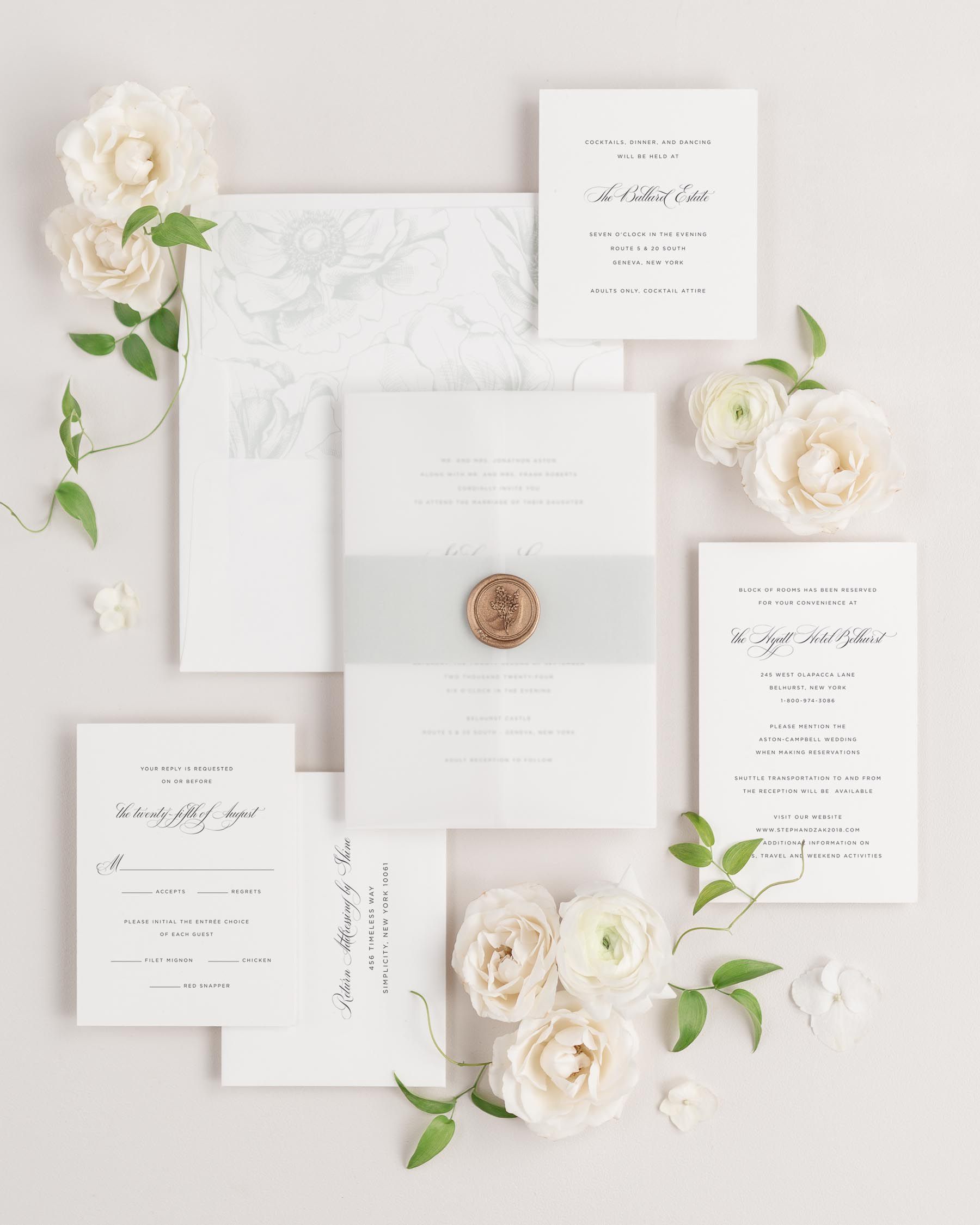 Delicate Elegance wedding invitations flat lay with sea salt anemones liner, sea salt belly band, translucent vellum jacket, and gold posy wax seal.