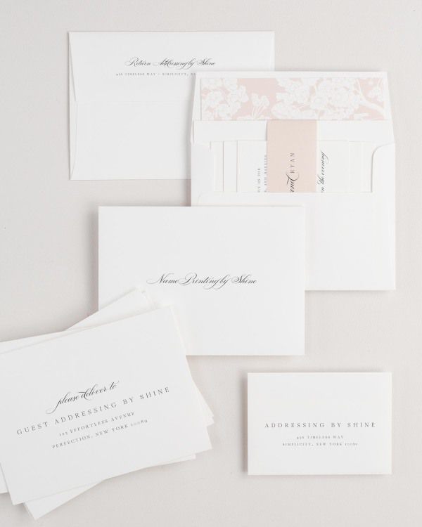 Ella wedding invitation envelopes with guest addressing, return addressing, and name printing services. Inner envelope features a petite fleur liner and rose gold belly band.