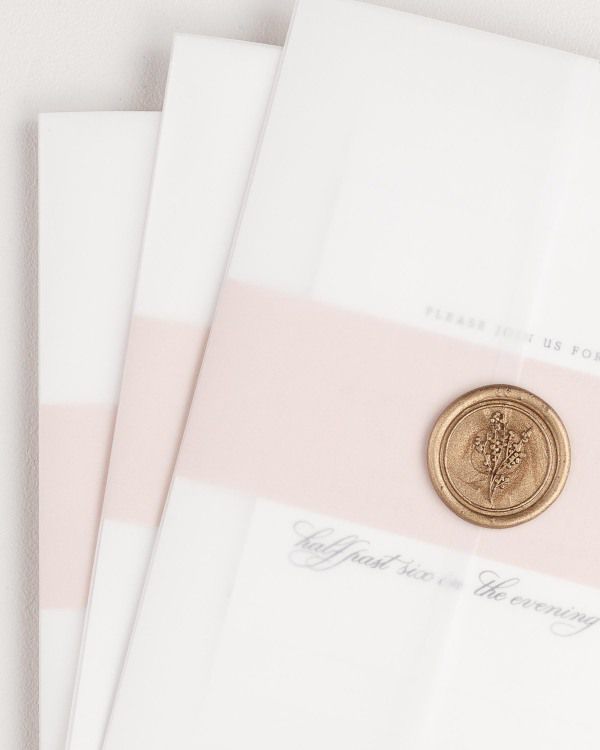 Ella wedding invitation with a rose gold belly band, translucent vellum jacket, and gold posy wax seal.