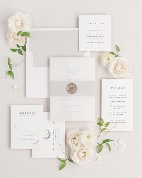 Emily wedding invitation with a stone belly band, translucent vellum jacket, and bronze florette wax seal.