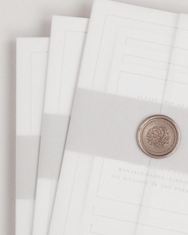 Emma wedding invitation with a belly band, translucent vellum jacket, and bronze florette wax seal.