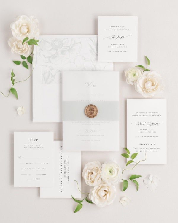 Gabriella wedding invitations flat lay with sea salt anemones liner, sea salt belly band, translucent vellum jacket, and gold posy wax seal.