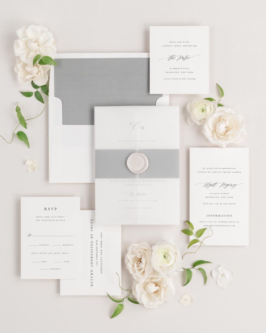 Gabriella wedding invitations flat lay with slate solid liner, slate belly band, translucent vellum jacket, and pearl florette wax seal.
