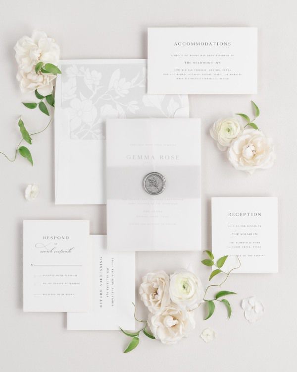 Gemma wedding invitations flat lay with soft gray magnolia liner, soft gray belly band, translucent vellum jacket.
