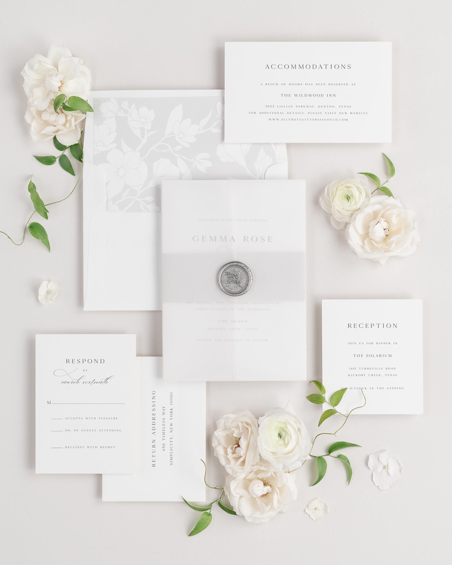 Gemma wedding invitations flat lay with soft gray magnolia liner, soft gray belly band, translucent vellum jacket.