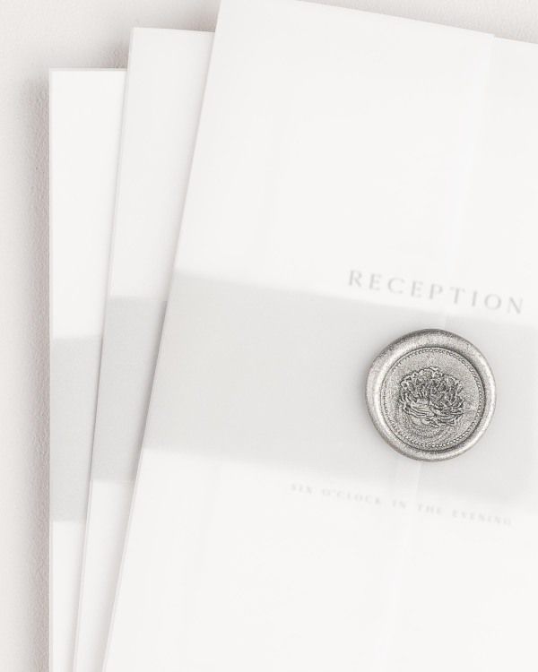 Gemma wedding invitation with a soft gray belly band, translucent vellum jacket, and silver florette wax seal.