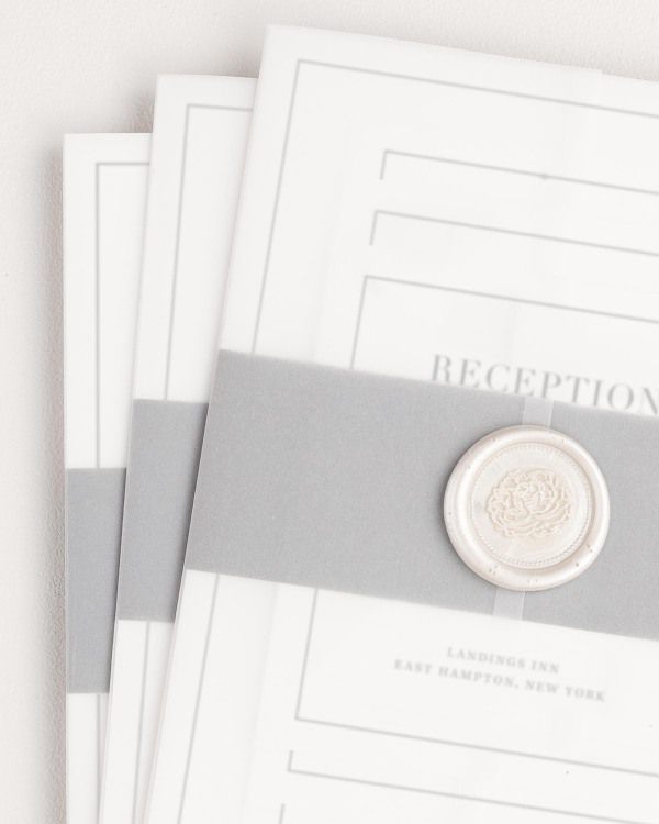 Glam Monogram wedding invitation with a slate belly band, translucent vellum jacket, and pearl florette wax seal.