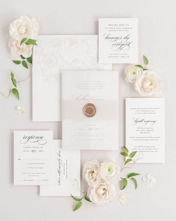 Haley wedding invitations flat lay with nude garden rose liner, nude belly band, translucent vellum jacket, and gold florette wax seal.