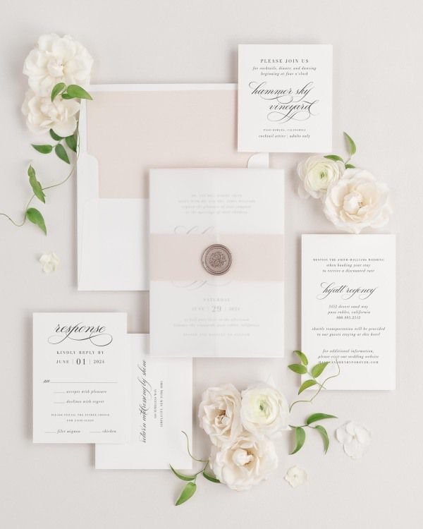 Haley wedding invitations flat lay with rose gold solid liner, rose gold belly band, translucent vellum jacket, and bronze florette wax seal.