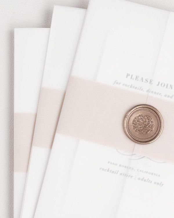 Haley wedding invitation with a rose gold belly band, translucent vellum jacket, and bronze florette wax seal.