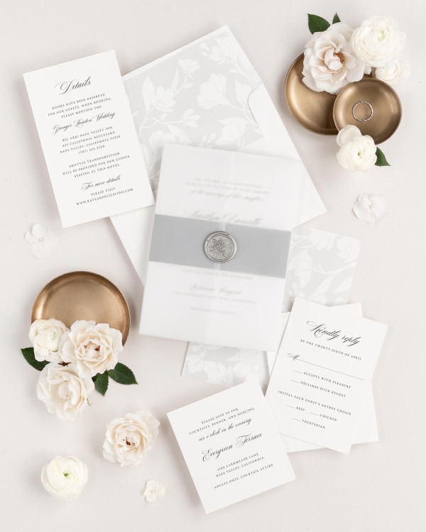 Kaitlyn wedding invitations flat lay with soft gray magnolia liner, slate belly band, and silver posy wax seal.