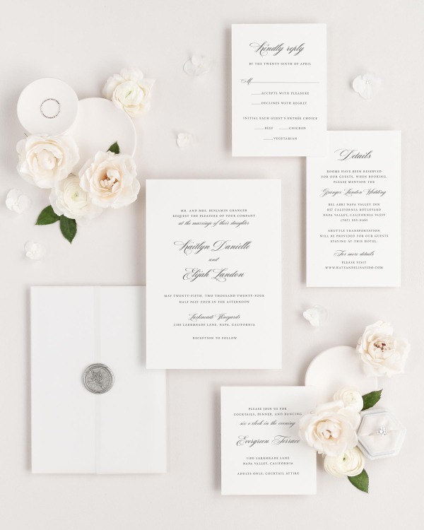 Kaitlyn wedding invitations flat lay with translucent vellum jacket, and silver posy wax seal.