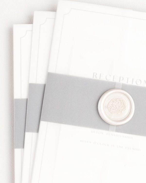 Kendall wedding invitation with a slate belly band, translucent vellum jacket, and pearl florette wax seal.