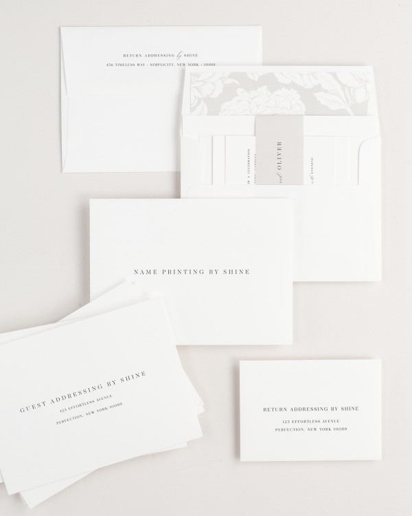 Leighton wedding invitation envelopes with guest addressing, return addressing, and name printing services. Inner envelope features a blooms liner and feather belly band.