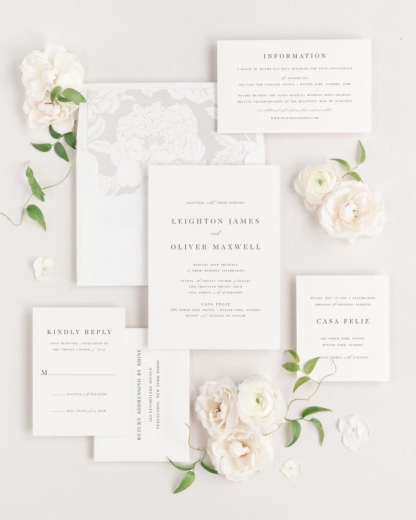 Leighton wedding invitations flat lay with feather blooms liner.