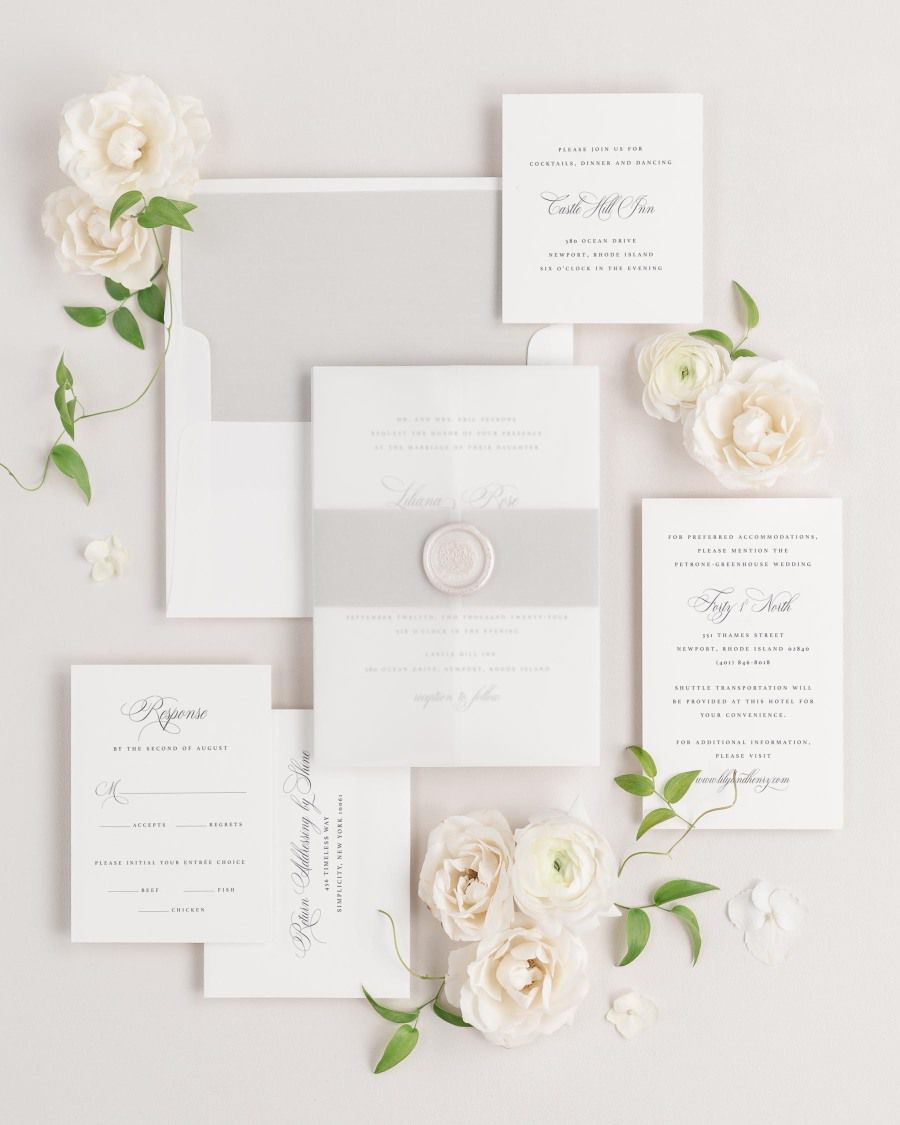 Liliana wedding invitations flat lay with stone solid liner, stone belly band, translucent vellum jacket, and pearl florette wax seal.