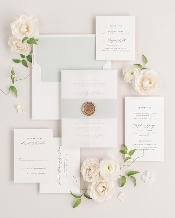 Lily wedding invitation with a sea salt belly band, translucent vellum jacket, and gold wreath wax seal.