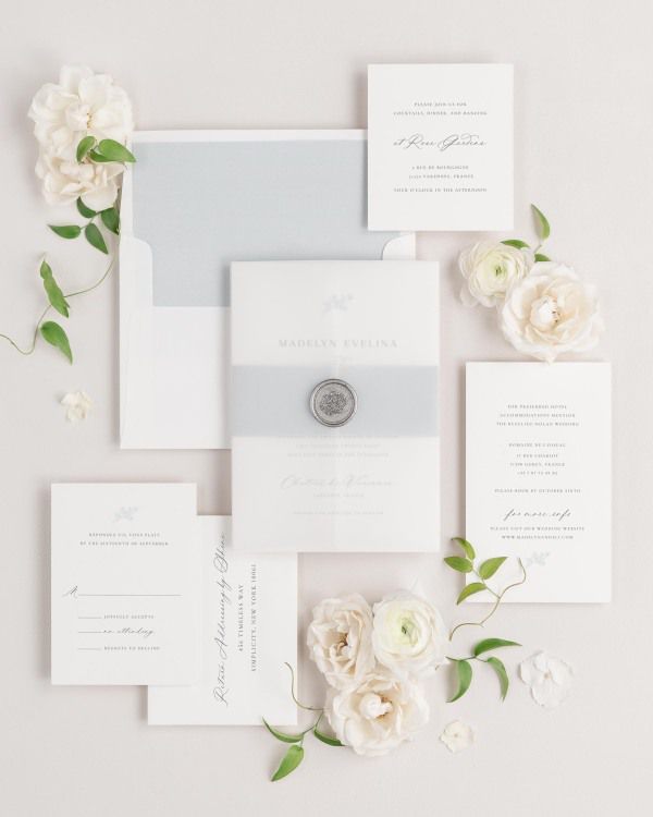 Madelyn wedding invitation with a cloud belly band, translucent vellum jacket, and silver florette wax seal.