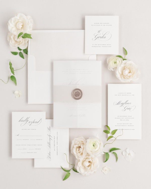 Nadia wedding invitations flat lay with nude solid liner, nude belly band, translucent vellum jacket, and bronze florette wax seal.