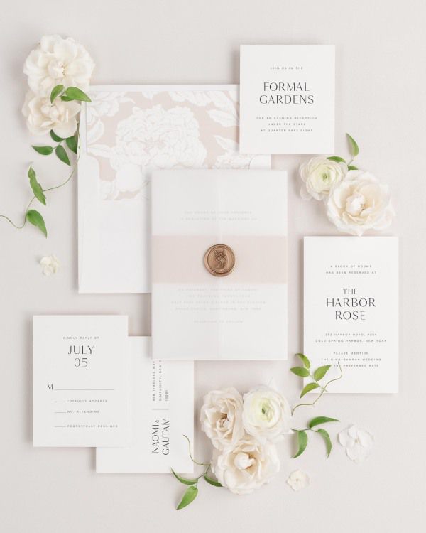 Naomi wedding invitations flat lay with rose gold blooms liner, rose gold belly band, translucent vellum jacket.