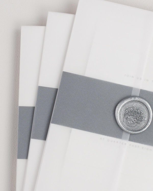 Naomi wedding invitation with a black belly band, translucent vellum jacket, and silver florette wax seal.