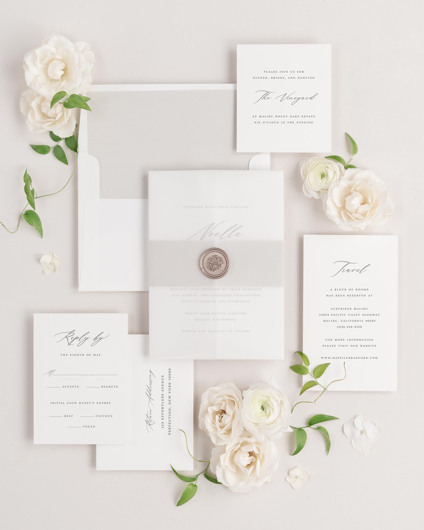 Noelle wedding invitations flat lay with stone solid liner, stone belly band, translucent vellum jacket, and bronze florette wax seal.