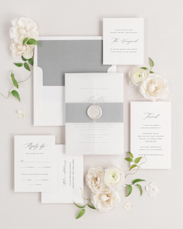 Noelle wedding invitations flat lay with slate solid liner, slate belly band, translucent vellum jacket, and pearl florette wax seal.