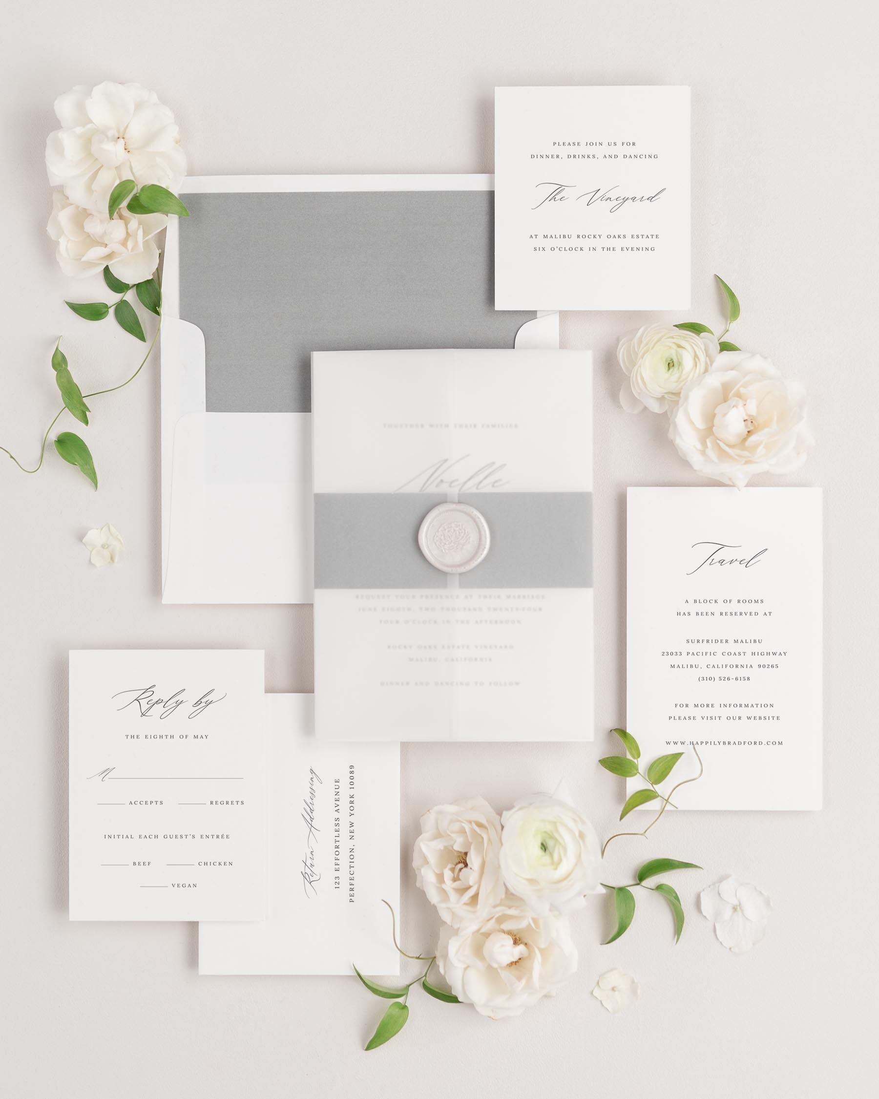 Noelle wedding invitations flat lay with slate solid liner, slate belly band, translucent vellum jacket, and pearl florette wax seal.