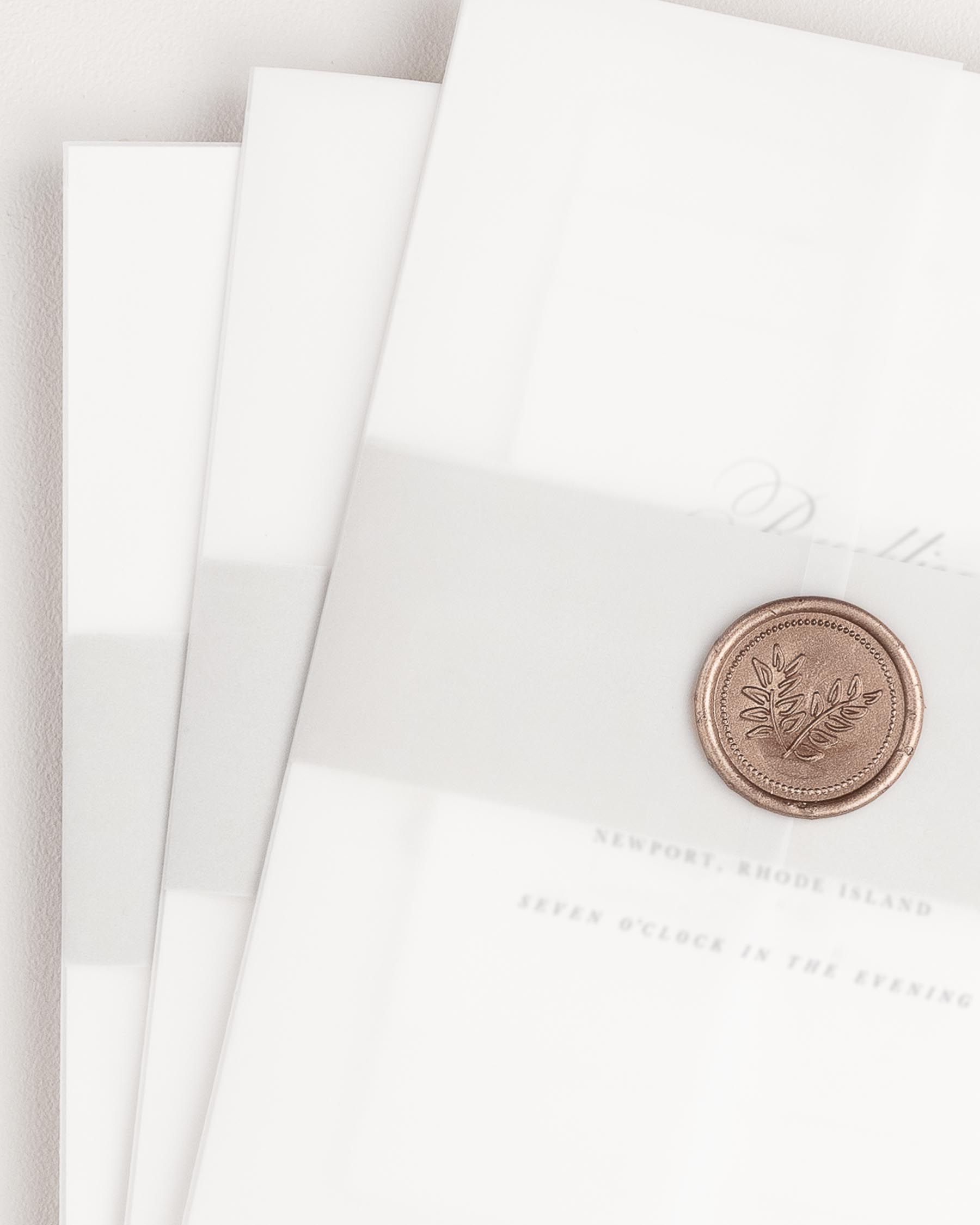 Penelope wedding invitation with a soft gray belly band, translucent vellum jacket, and bronze wreath wax seal.