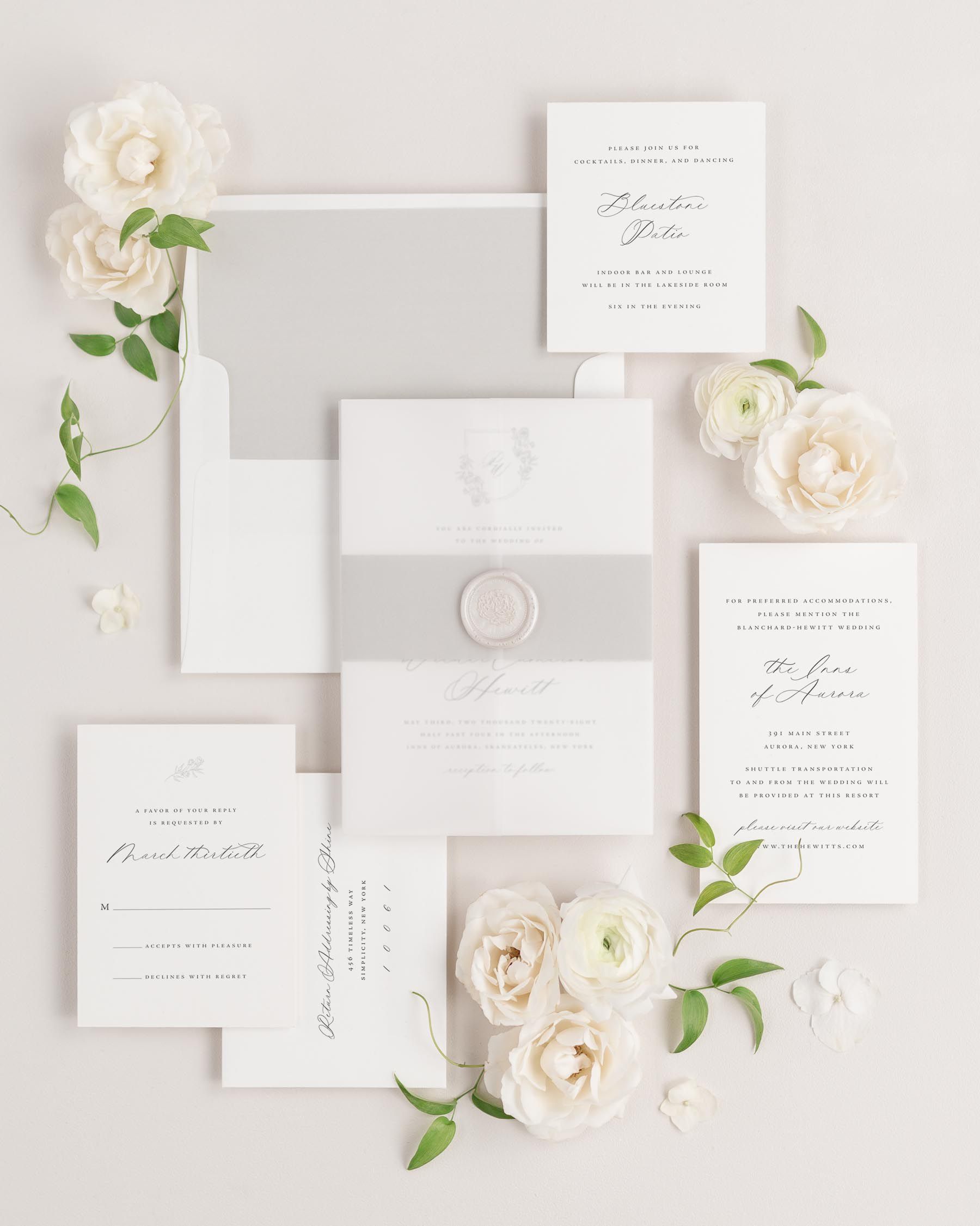 Phoebe wedding invitation with a stone belly band, translucent vellum jacket, and pearl florette wax seal.