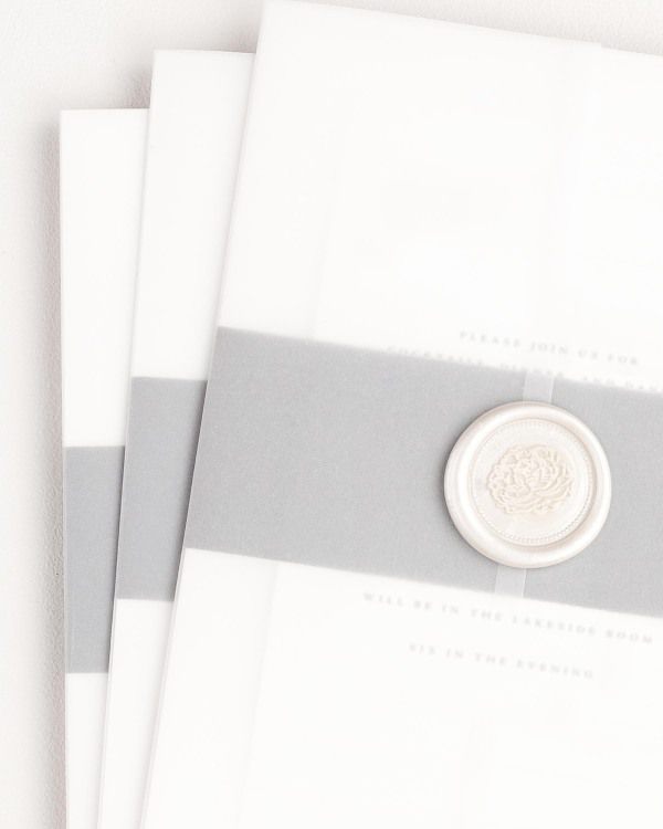 Phoebe wedding invitation with a slate belly band, translucent vellum jacket, and pearl florette wax seal.