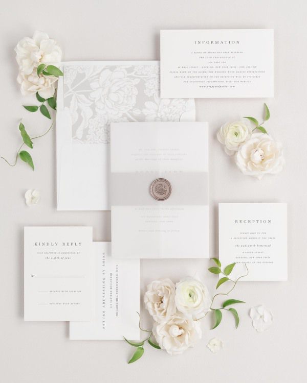 Poppy wedding invitations flat lay with feather hydrangea liner, feather belly band, translucent vellum jacket, and bronze florette wax seal.