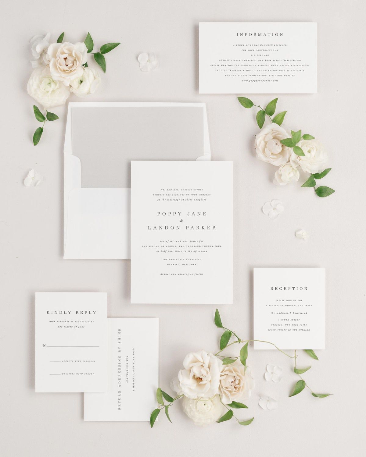 A Poppy wedding invitation suite is styled on a neutral background with florals and greenery. You can clearly see each enclosure, and the envelope features a stone colored envelope liner.