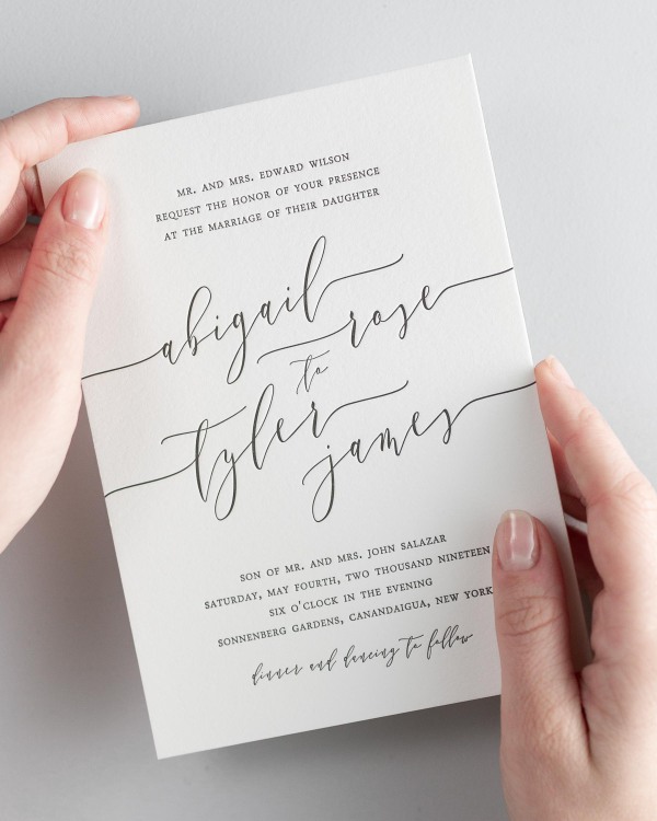 Bride holding her 5x7” Romantic Calligraphy letterpress wedding invitation.