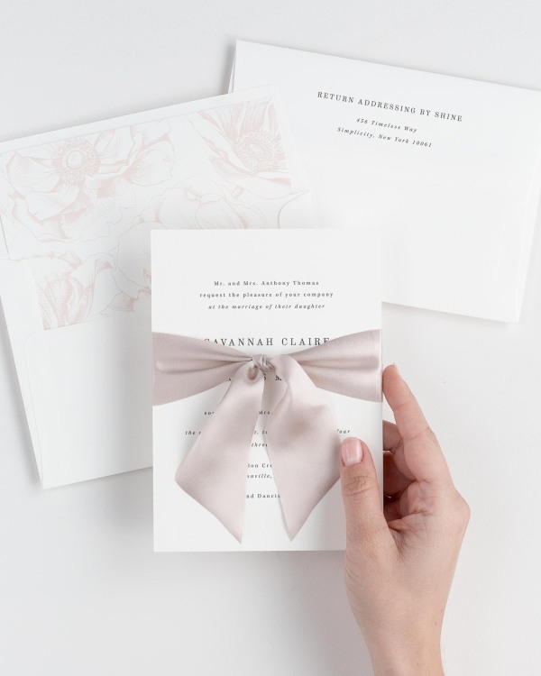 Bride holding Savannah wedding invitation tied with antoinette ribbon.