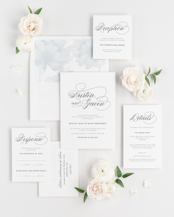 Script Elegance wedding invitations flat lay with ice blue watercolor peonies liner.