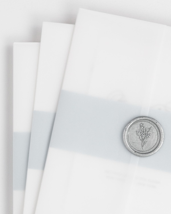 Script Elegance wedding invitation with a ice blue belly band, translucent vellum jacket, and silver posy wax seal.