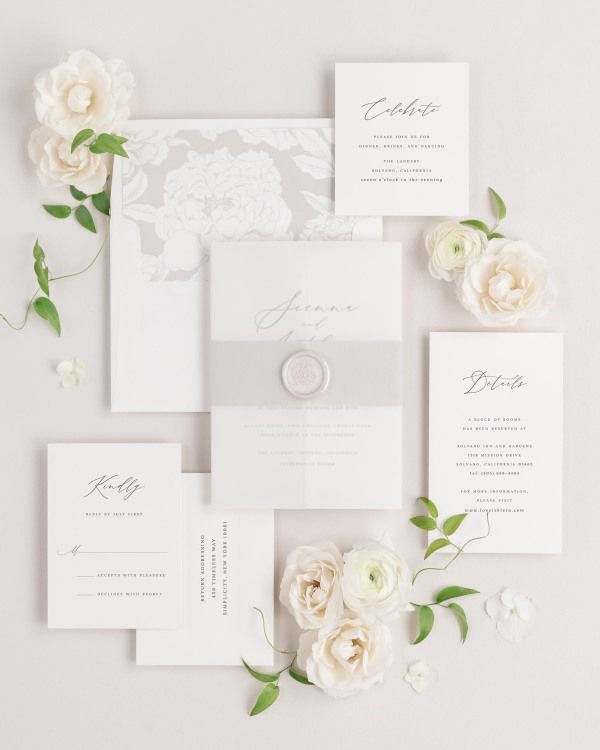 Sienna wedding invitations flat lay with stone blooms liner, stone belly band, translucent vellum jacket, and pearl florette wax seal.