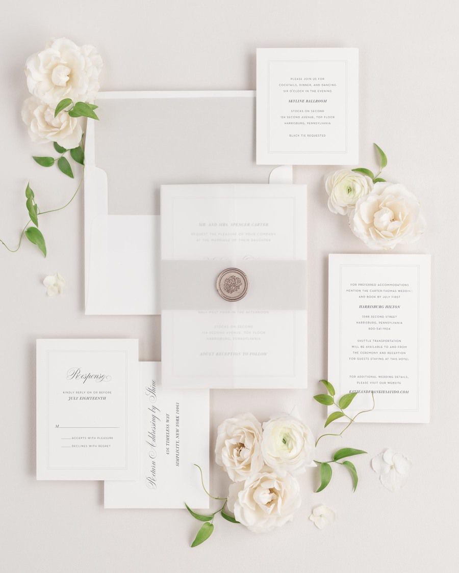 Simply Classic wedding invitations flat lay with stone belly band, translucent vellum jacket, and bronze florette wax seal.